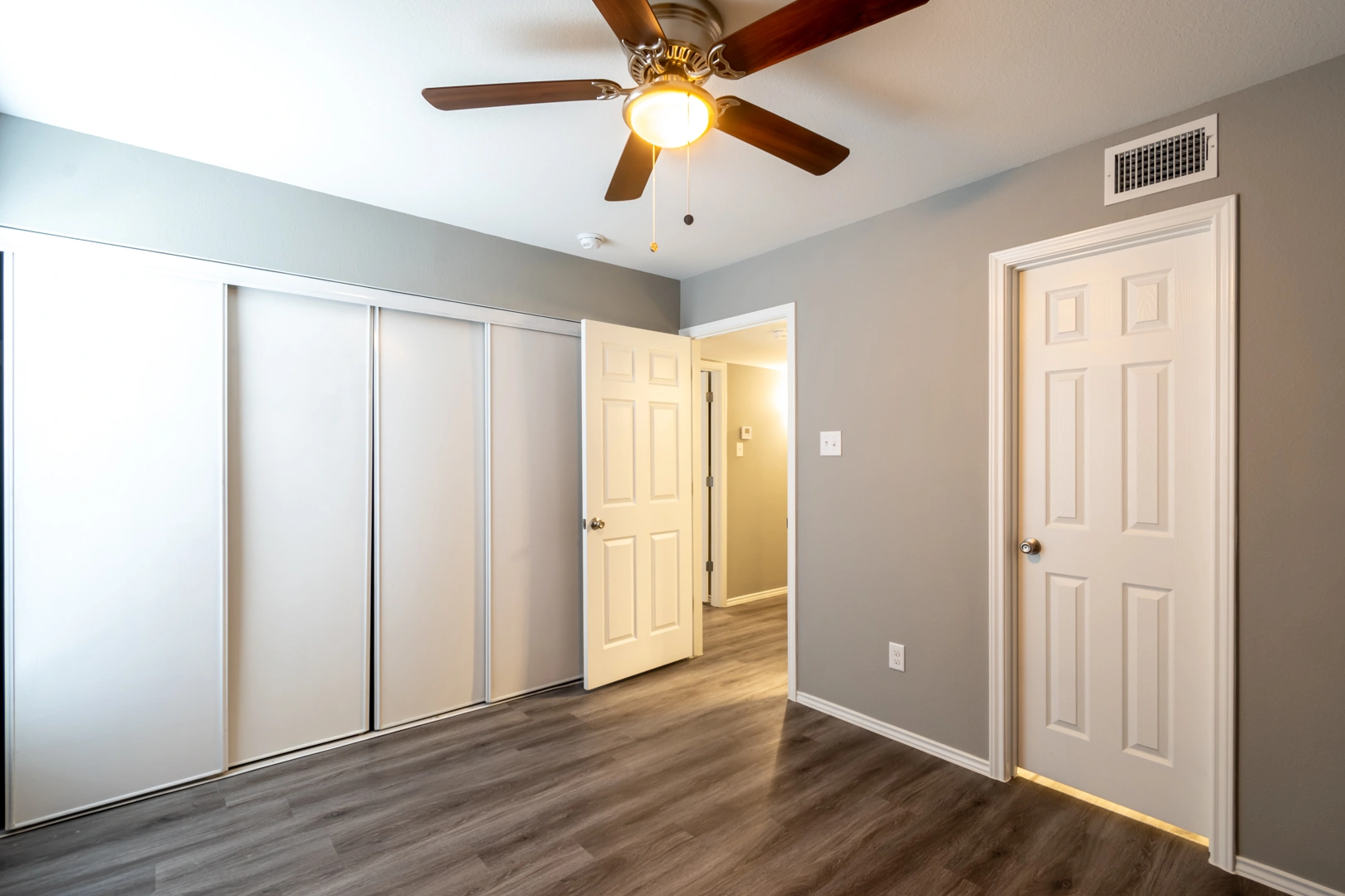 Bedroom with sliding closet doors at Crossings at Irving in Irving, Texas